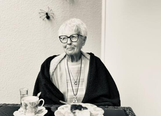 Ältere Frau sitzt nachdenklich am Kaffeetisch – ein Moment zwischen Abschied und Gegenwart