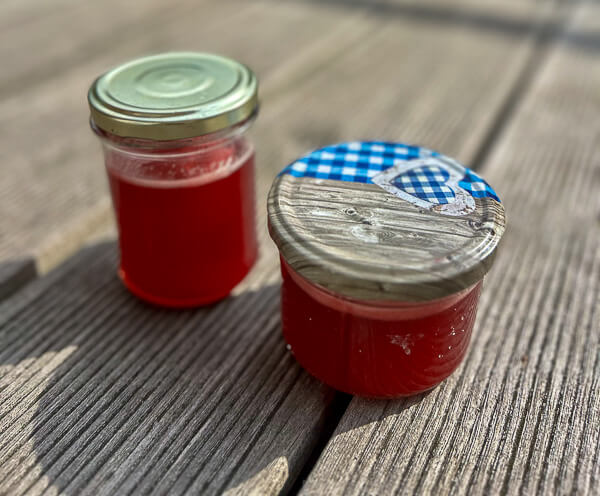 Verschlossene Gläser mit rotem Johannisbeer-Gelee auf Holzuntergrund – bereit für den Vorrat.