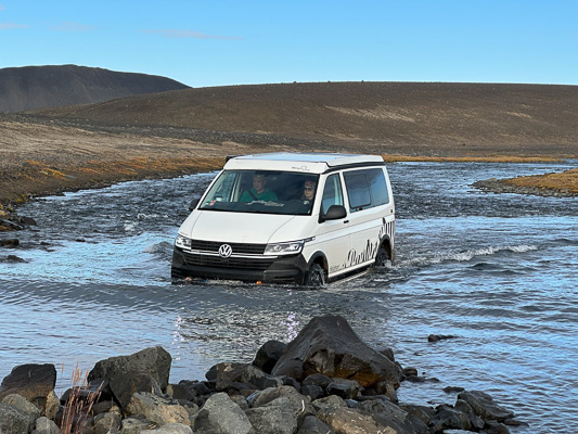 VW Bulli arbeitet sich durch einen Fluß – Offroad-Reisepanne im Gelände - eine Reise die prägt.