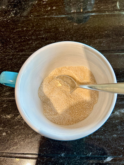 Pektin-Zuckermischung in einer weißen Tasse mit Löffel auf dunkler Küchenplatte