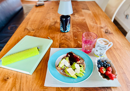 Frühstücksteller mit Avocado-Brot, Gelee, Kaffee, Beeren – ein stilles Fest in Türkis und Holz.