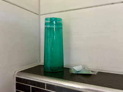 Eine durchsichtige Shampooflasche ohne Etikett steht allein im Badregal – stille Rebellion gegen visuelle Vereinnahmung.