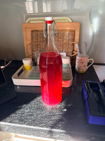 Himbeerroter Jungwein in Bügelflasche, leuchtend im Sonnenlicht