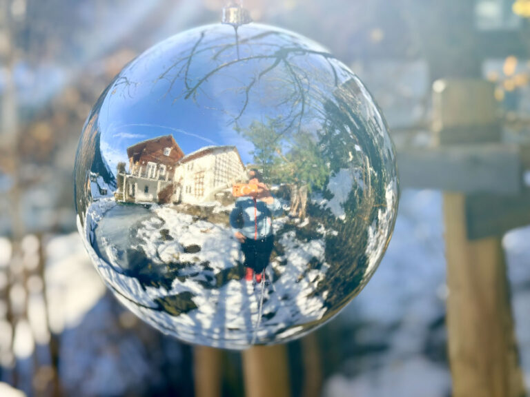 Haus im Winter gespiegelt in großer Glaskugel