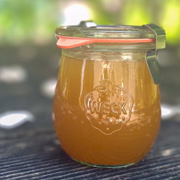 Holunderblütengelee in einem Weck-Glas, goldgelb, im Gegenlicht.