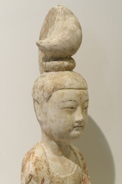 Kopf und Schultern einer Tonfigur: Hofdame der Tang-Zeit mit hoch aufgetürmter Frisur, gesenktem Blick und schlichtem Gewand.